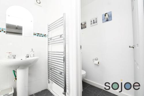 a white bathroom with a toilet and a sink at Charming and spacious 3 bedroom house very close to the beach in Lowestoft