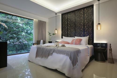 a bedroom with a large bed and a large window at Sanctoo Suites & Villas in Gianyar