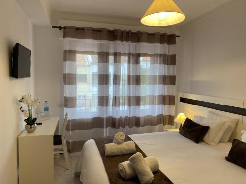 a bedroom with a bed and a desk and a window at The Rock Guest House in Ponta Delgada
