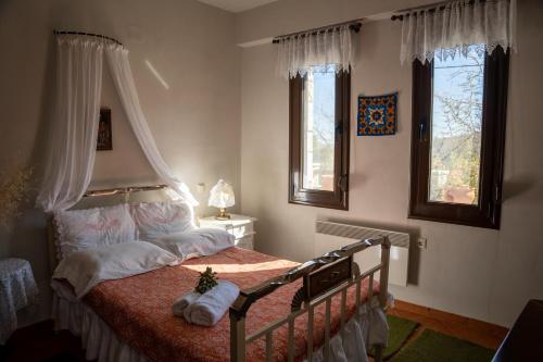 1 dormitorio con 1 cama con dosel y 2 ventanas en Margarita's House, en Kalyvia Fylaktis