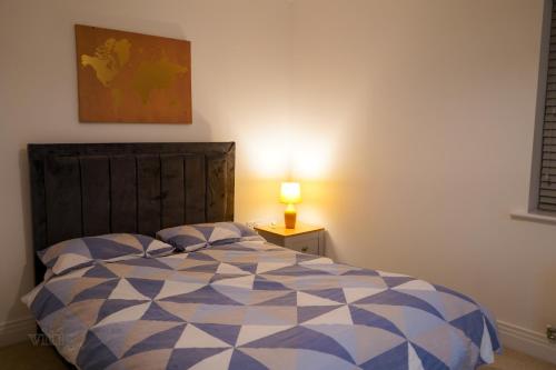 een slaapkamer met een bed en een lamp op een tafel bij A1M Hampton Lakes Brand New Entire House in Peterborough