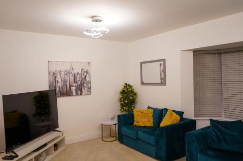 sala de estar con sofá azul y TV en A1M Hampton Lakes Brand New Entire House en Peterborough