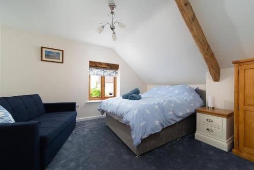 um quarto com uma cama, um sofá e uma janela em The Old Piggery em Stoke Rivers