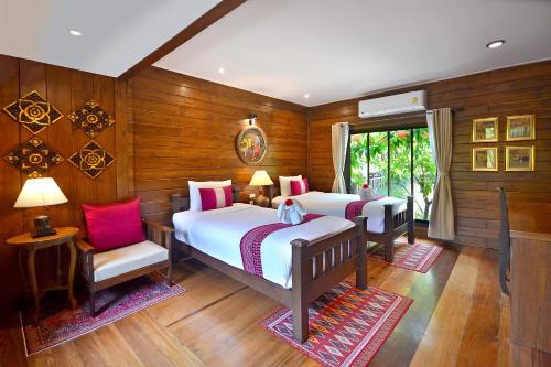 two beds in a room with wooden walls at Thai Thai Sukhothai Resort in Sukhothai