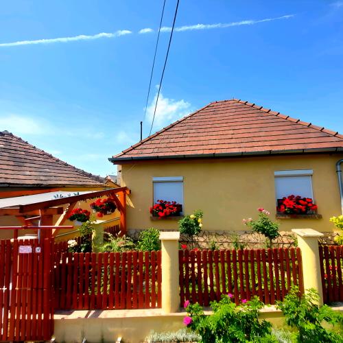 a house with a red fence and flowers at Kata Vendégház in Sátoraljaújhely