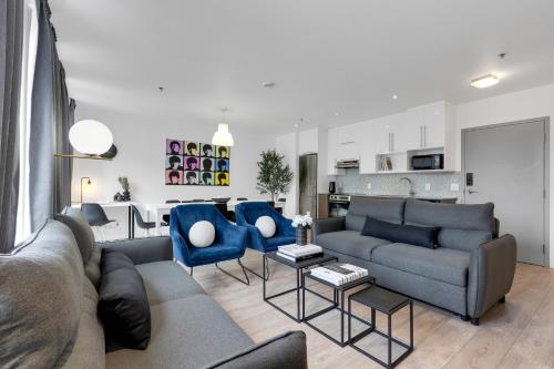 a living room with a couch and two blue chairs at LiV MTL Downtown Montreal Spacious Suites in Montreal