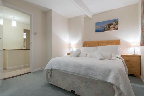 a bedroom with a large white bed with white pillows at Talland Croft in Crantock