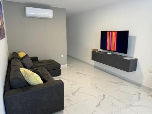 a living room with two couches and a flat screen tv at Emerald Suite in St Paul's Bay