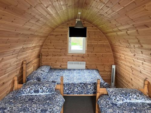 una camera con tre letti in una camera in legno di Gateway Glamping Pods a Llanelli