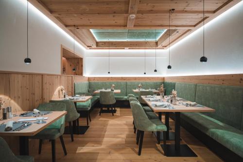 a dining room with tables and green booths at Schönblick - Sport & Active Hotel in Brunico