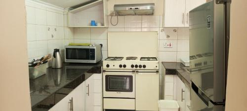 a white kitchen with a stove and a microwave at One bedroom panthehouse in Kisumu