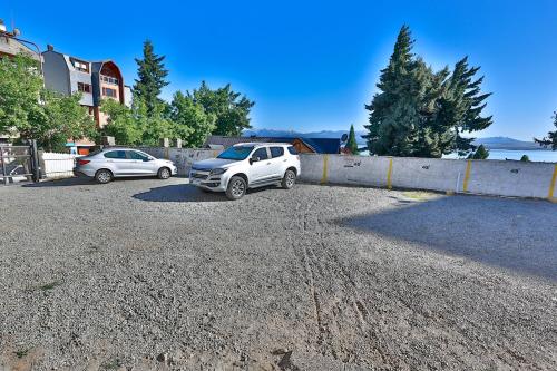 two cars parked in a gravel parking lot at Hotel Tierra Gaucha in San Carlos de Bariloche