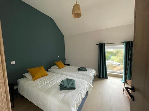 2 camas en una habitación con paredes verdes y ventana en La Grange d'Haversin, en Ciney