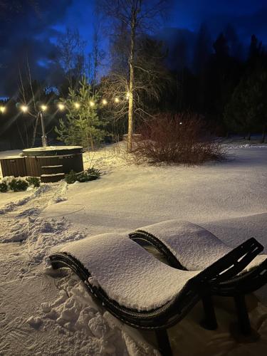 a bench covered in snow at night with lights at ANDO Villa with wood stove sauna in Selgas