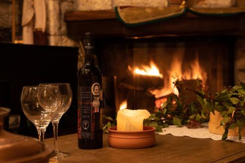 a bottle of wine and glasses on a table with a fireplace at Margarita's House in Kalyvia Fylaktis