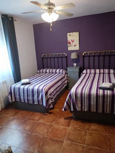 two beds in a room with purple walls at PINAR DE LAS CABAÑUELAS in Villanueva de Duero