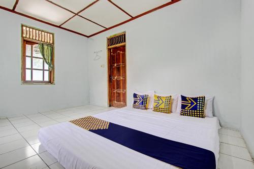 um quarto branco com uma cama com almofadas azuis e amarelas em SPOT ON 93592 Pondok Backpackers Ardafa Jogja em Manisrenggo