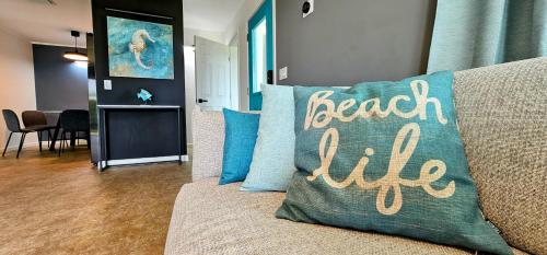 Un sofá con una almohada que dice vida en la playa en Luxury beach villa in paradise. en Treasure Cay