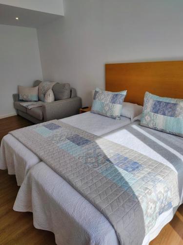 a bedroom with two beds and a couch at Apartamentos La Toja in O Grove