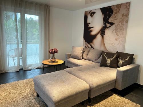 a living room with a couch and a large painting of a woman at Alex Design Appartment in Rastatt
