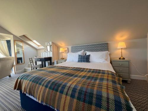 a bedroom with a large bed with a plaid blanket at Y Stabl in New Quay
