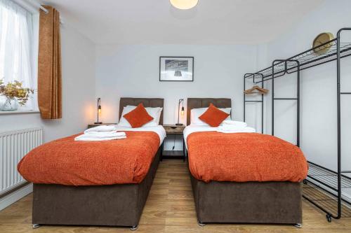 a bedroom with two beds with orange sheets at Charming 3-Bed Townhouse in Vibrant Ealing in Ealing