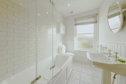a white bathroom with a tub and a sink at St Vincent 3 bedroom property in Bristol