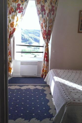 a bedroom with a window with a bed in front of it at Auberge Hôtel de Tournemire - Cantal in Tournemire