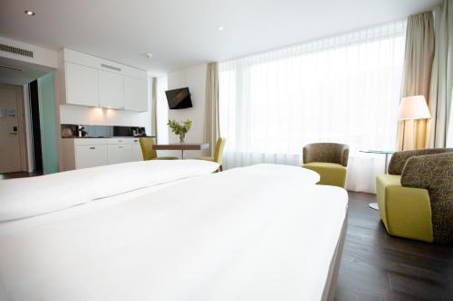 a hotel room with a bed and a kitchen at Mercure Chur City West in Chur