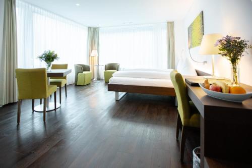 a hotel room with a bed and a table and chairs at Mercure Chur City West in Chur