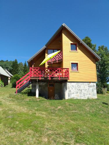 une maison dotée d'un balcon jaune et rouge. dans l'établissement Chalet nordique 31, à La Féclaz
