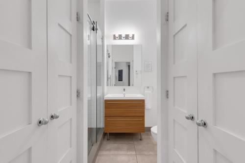 a white bathroom with a sink and a mirror at LiV MTL Downtown in Montréal