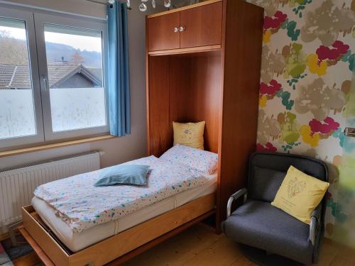 a small bedroom with a bed and a chair at Erholung am Vulkanradweg - 4 Sterne DTV Zertifiziert in Bad Salzschlirf