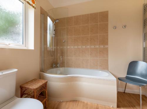 uma casa de banho com uma banheira branca e uma cadeira. em 5 Bed in Woodbridge 72724 em Woodbridge