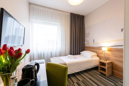 una habitación de hotel con una cama y un jarrón de flores en Hotel Maraton, en Szamotuły