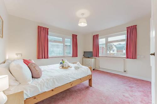 - une chambre avec un grand lit et des rideaux rouges dans l'établissement Coast Haven - Norfolk Cottage Agency, à Sheringham