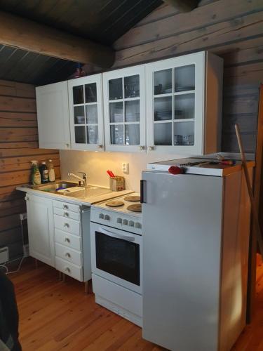 La cuisine est équipée de placards blancs et d'un réfrigérateur blanc. dans l'établissement Bjørgebu Camping AS, à Mysusæter