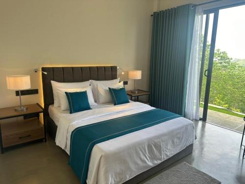 a bedroom with a large bed and a large window at Amore Resorts in Kobbekaduwa