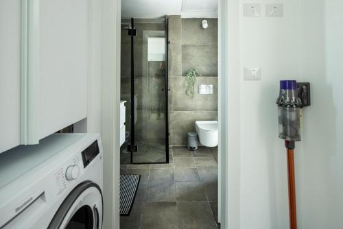 a bathroom with a shower and a washing machine at HaCarmel Market Vibrat Apartment by Sea N' Rent in Tel Aviv