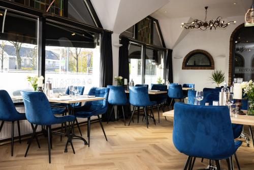 a restaurant with blue chairs and tables and windows at Hotel De Rustende Jager in Nieuw-Vennep