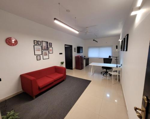 a living room with a red couch and a table at Lotus Korean Hotel in Bengaluru