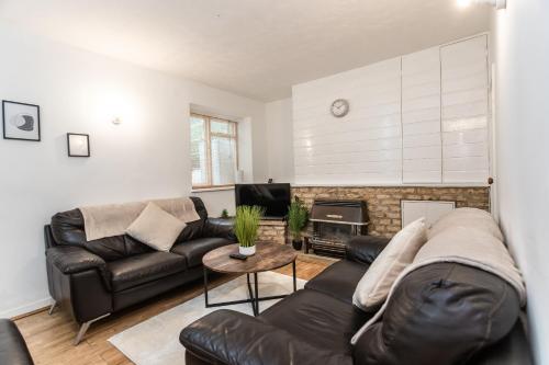 a living room with a leather couch and a fireplace at April Disc - Long Stay - Contractors in Swindon