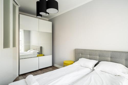 ein Schlafzimmer mit einem großen weißen Bett und einem Spiegel in der Unterkunft RentPlanet - Apartament Dubois in Breslau