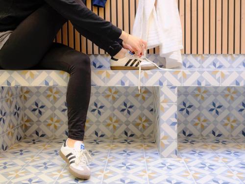 a person sitting on a bench wearing white shoes at Logis Hôtel de l'Europe in Poitiers