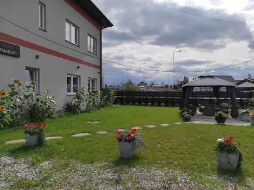 a yard with potted flowers and a gazebo at Apartamenty KOMBI in Nowy Targ