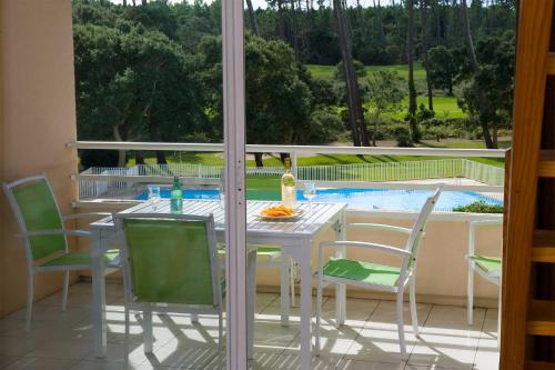 une table et des chaises blanches sur une terrasse avec piscine dans l'établissement Madame Vacances Les Appartements de Moliets, à Moliets-et-Maa