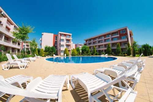 a group of white lounge chairs and a swimming pool at Nessebar Fort Club Apartments in Sunny Beach
