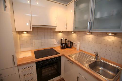 a kitchen with white cabinets and a sink at Landhaus Kaiser zum Strande - b47256 in Bastorf