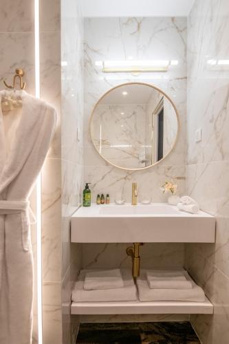 a white bathroom with a sink and a mirror at Hôtel Petit Palais in Nice