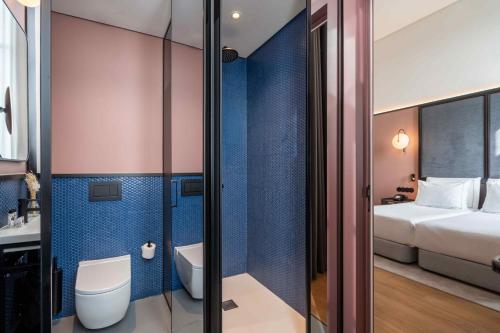 un bagno con servizi igienici e un letto in una camera. di The Editory Riverside Hotel, an Historic Hotel a Lisbona